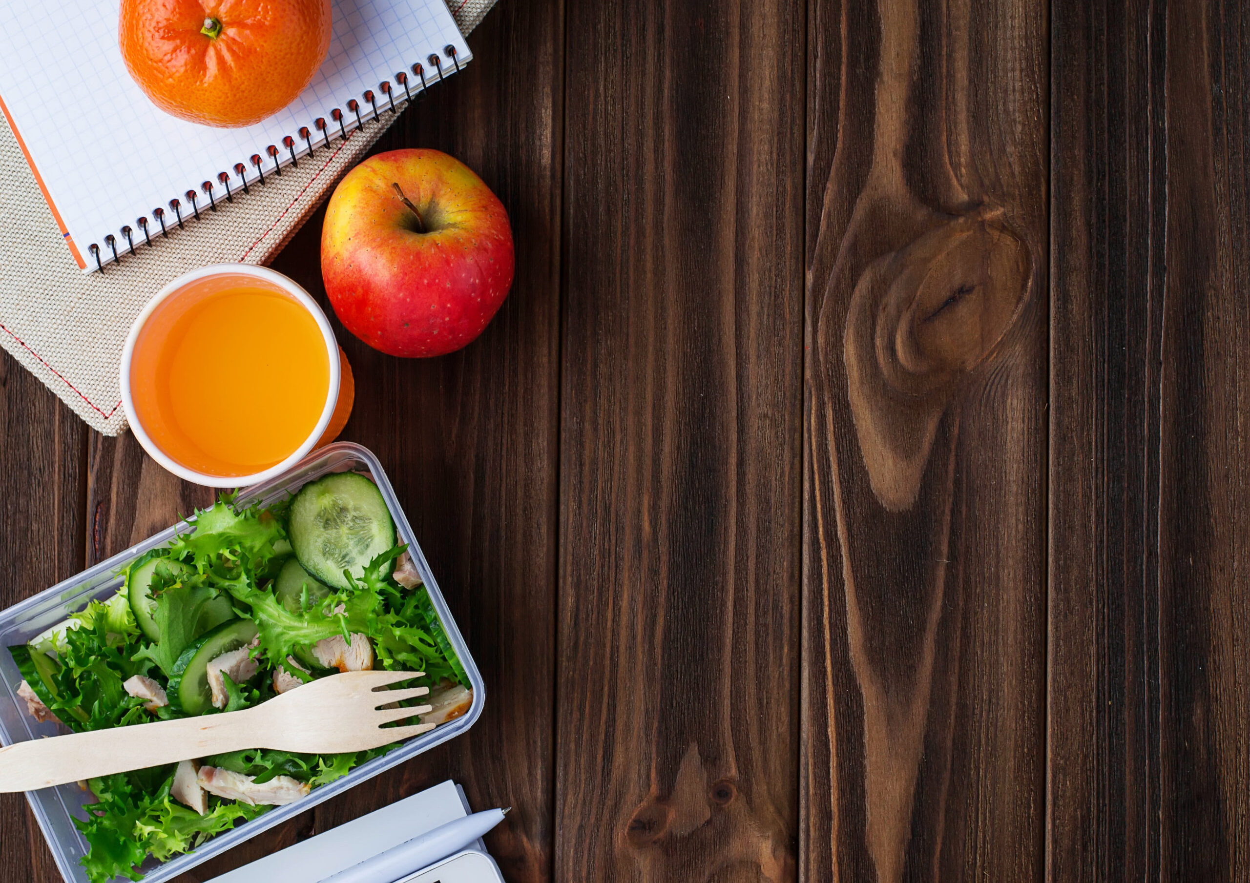 Lunch box with salad, apple, tangerine and juice.