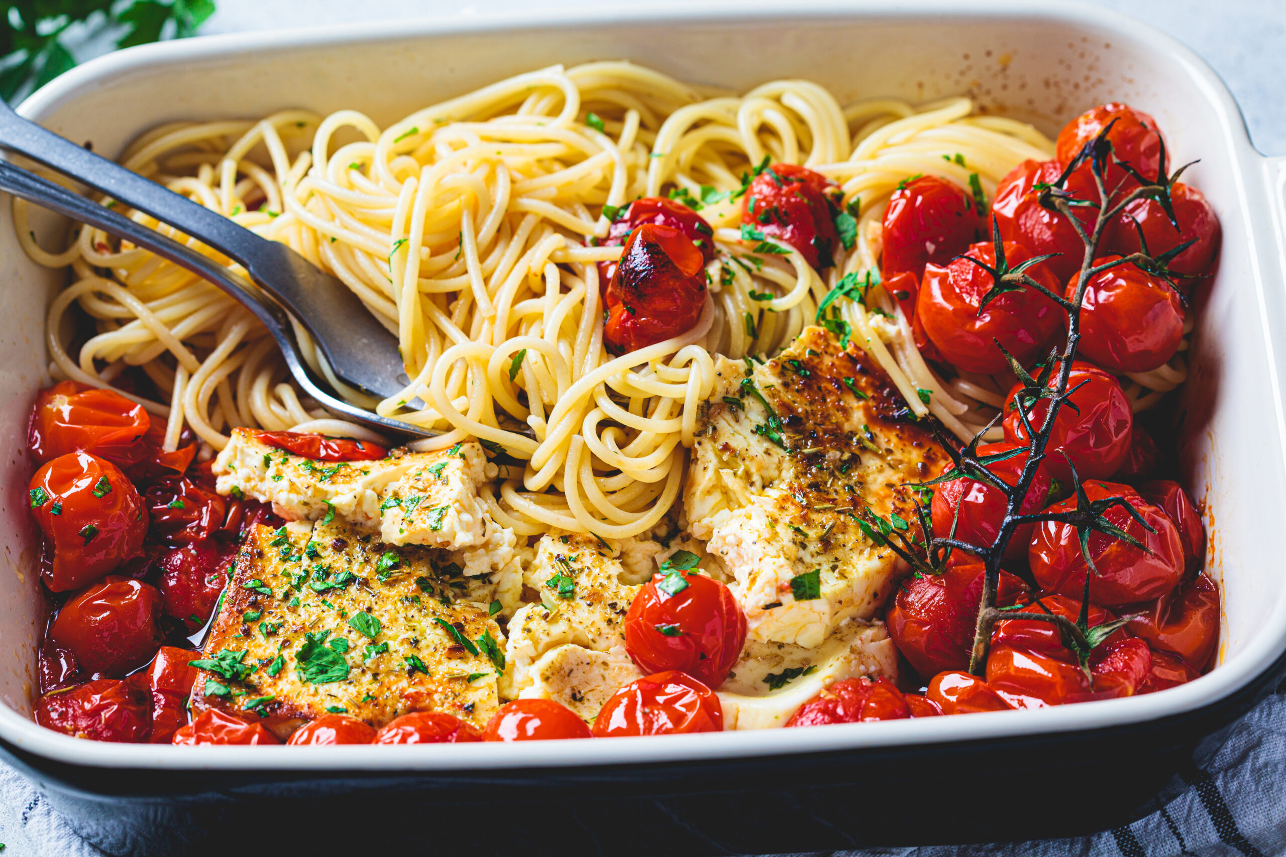 Baked feta cheese with tomato and spaghetti pasta in dish. Trend